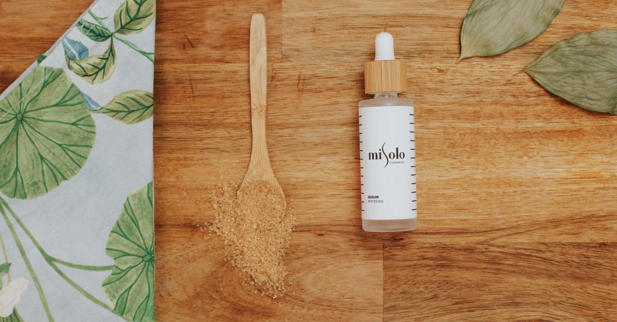 Botol skincare dengan pump pada latar kayu dan daun, eksfoliasi kimiawi