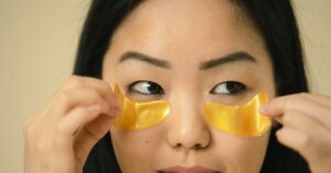 Wanita Asia mengaplikasikan patch bawah mata emas untuk kantung mata