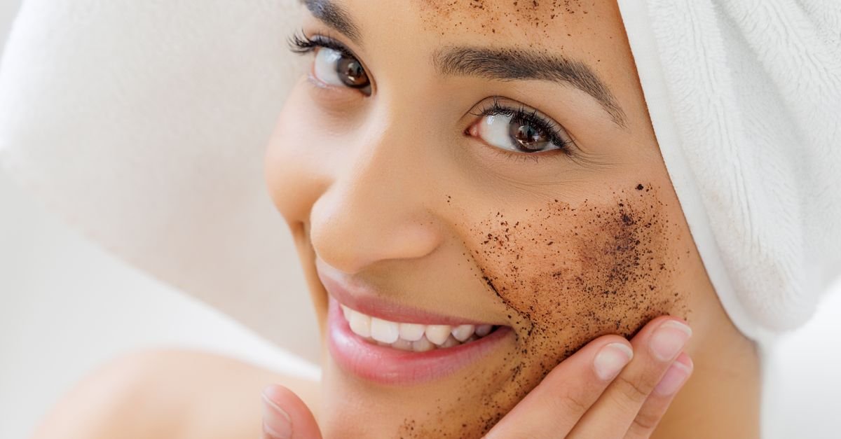Wanita dengan handuk di kepala mengaplikasikan masker wajah eksfoliasi alami, tersenyum