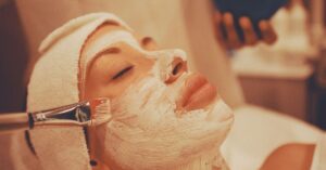 Wanita dengan masker tanah liat di wajah, perbandingan facial vs mikrodermabrasi