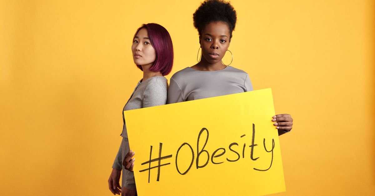 Dua perempuan memegang papan kuning bertuliskan #Obesity untuk kampanye kesadaran obesitas
