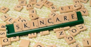 Huruf Scrabble menyusun kata SKINCARE pada latar merah, kamus istilah