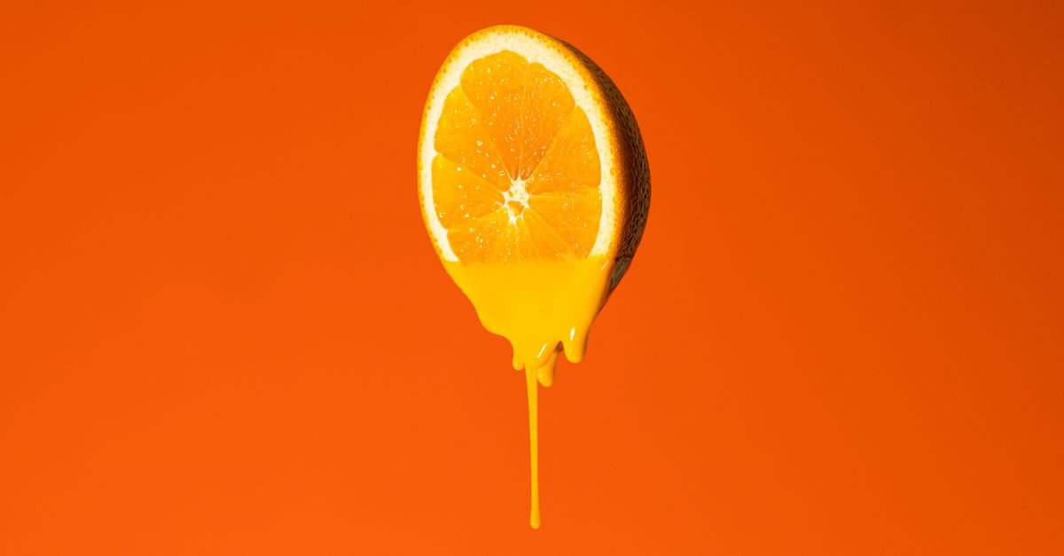 Tetesan kuning vitamin C pada latar oranye, konsep serum pencerah kulit