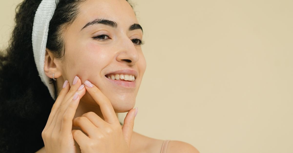 Wanita tersenyum mengaplikasikan perawatan kulit, transisi skincare