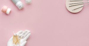 Flatlay produk skincare dan alat kecantikan di latar pink lembut
