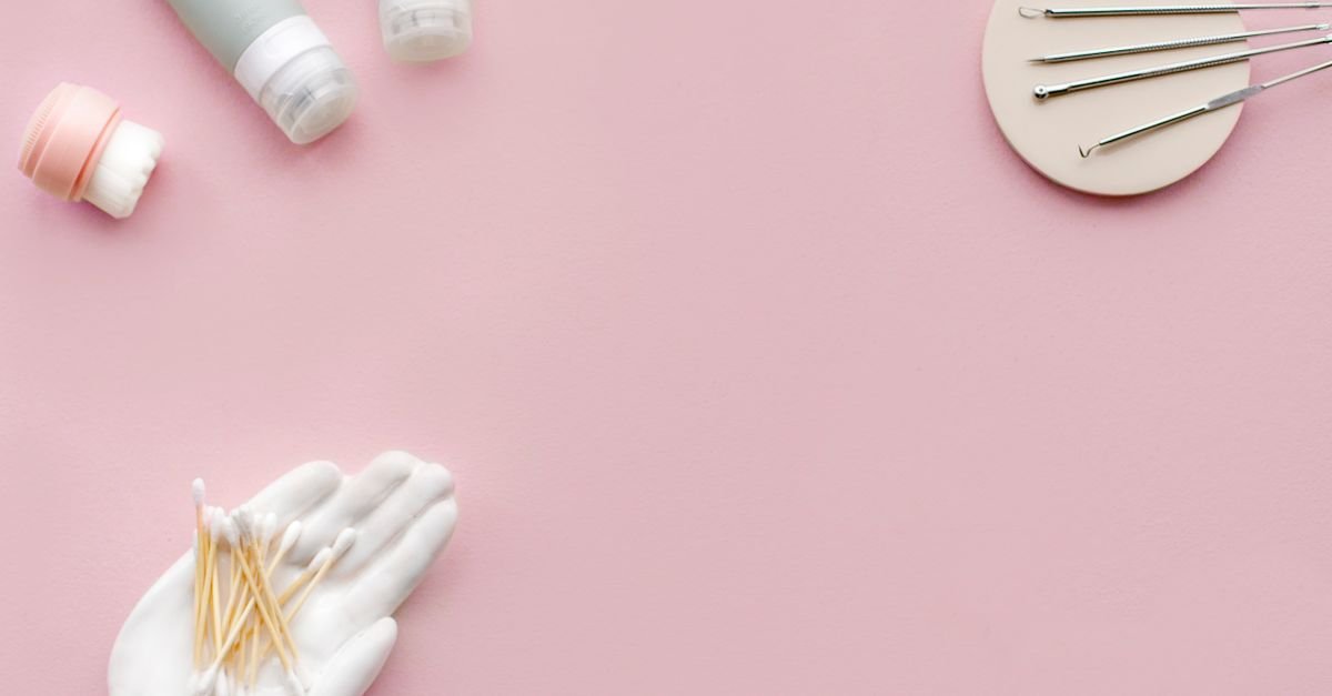 Flatlay produk skincare dan alat kecantikan di latar pink lembut