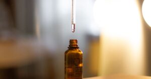 Botol kaca amber dengan pipet meneteskan serum di latar hangat