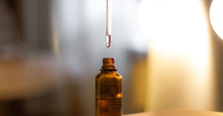 Botol kaca amber dengan pipet meneteskan serum di latar hangat