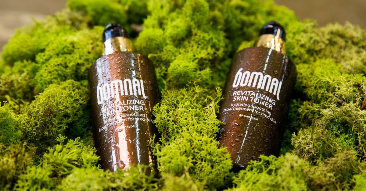 Botol toner pada latar hijau moss, produk toner untuk kulit berminyak